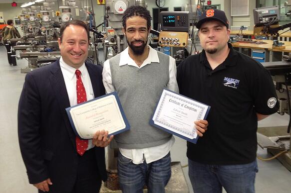 Edrick Smith, a Marlin Steel machinist and new graduate of the Magna Baltimore Technical Training Center, with Marlin Steel President Drew Greenblatt and Marlin Production Manager Andy Croniser