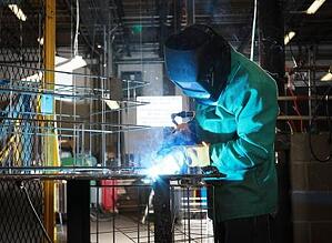 Marlin Steel worker welding a wire form.