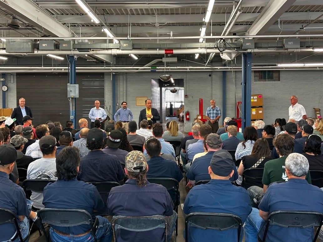 Executive team presenting to employee audience gathered on the manufacturing workshop.